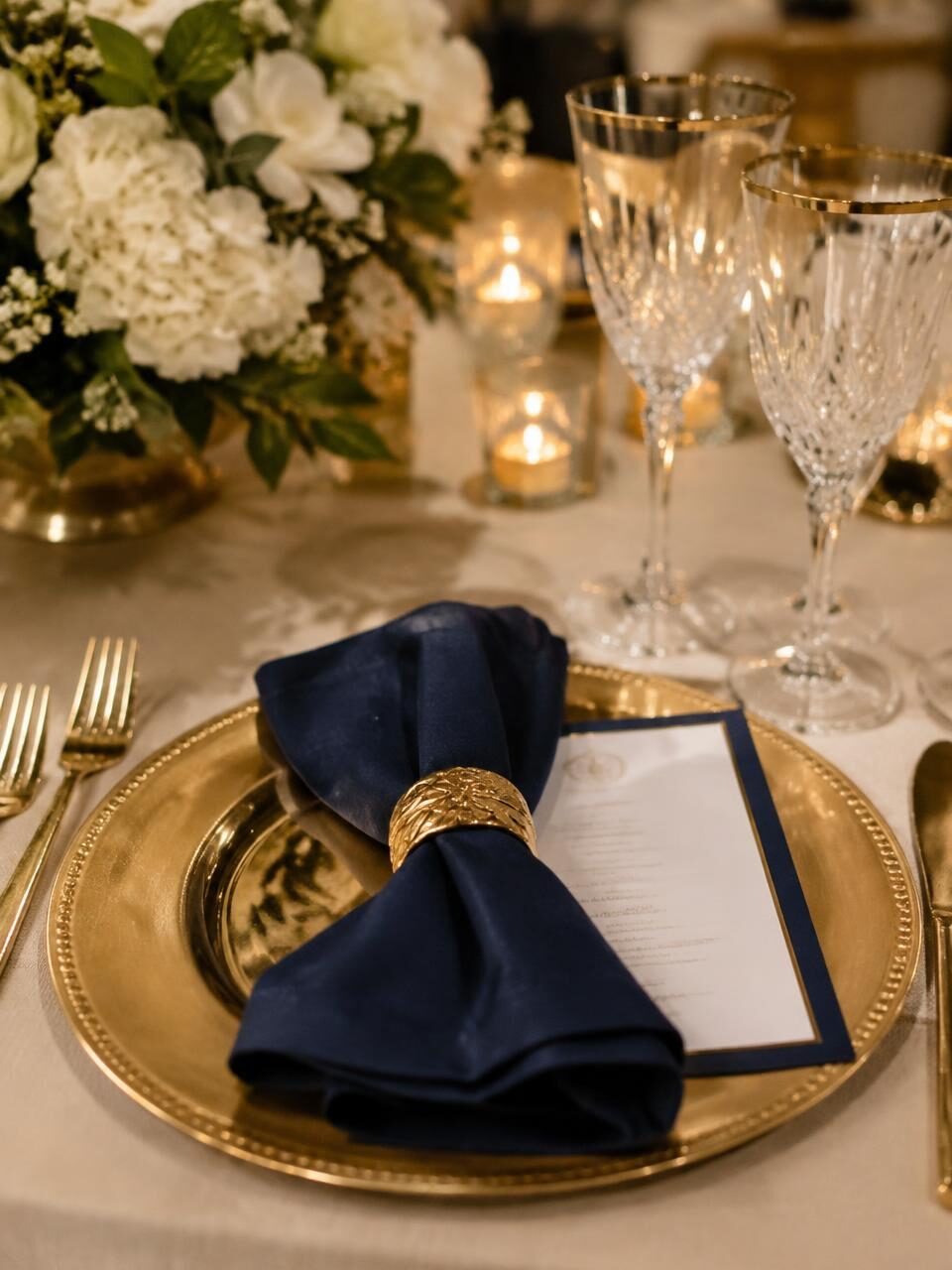 Place setting with navy napkin, gold charger and crystal glassware